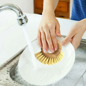 Round bamboo ring-handle kitchen scrub brush with natural sisal bristles on a white background, handheld dish and pot cleaning brush.