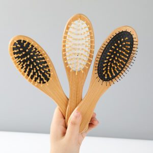 Bamboo paddle hair brush with rubber cushion and wooden handle for gentle scalp massage.