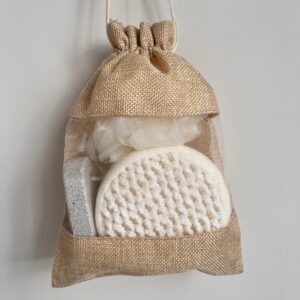 Bath body gift set in a linen tote bag with natural loofah sponges, scrubbing stone for feet, and bath ball.
