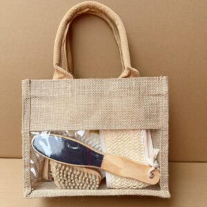 Natural bath and body set with dry body brush, loofah sponges, pumice stone, and more, neatly arranged in a linen handbag.