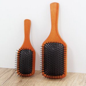 Detangling brush for hair with rubber cushion base and wooden handle, designed for scalp massage and smooth brushing.