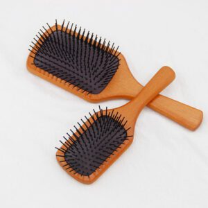 Detangling brush for hair with rubber cushion base and wooden handle, designed for scalp massage and smooth brushing.