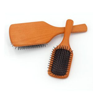 Detangling brush for hair with rubber cushion base and wooden handle, designed for scalp massage and smooth brushing.