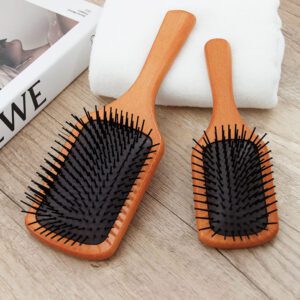 Detangling brush for hair with rubber cushion base and wooden handle, designed for scalp massage and smooth brushing.
