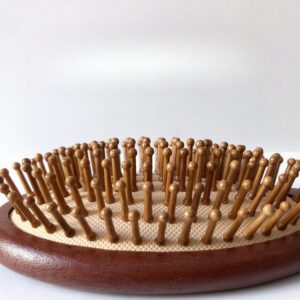 Wooden hair growth comb with rounded massage pins, designed to stimulate the scalp and support healthy brushing routines.