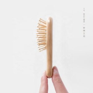 Small wooden hair brush for children with airbag cushion and rounded massage pins.