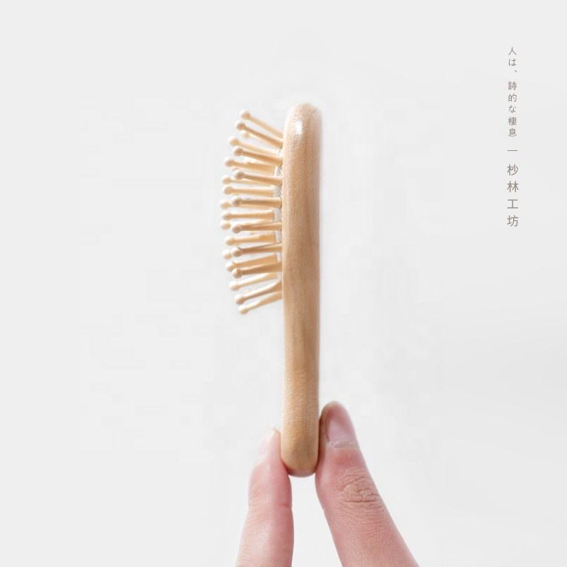 Small wooden hair brush for children with airbag cushion and rounded massage pins.