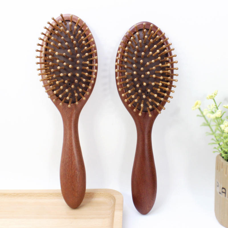 Round wooden hair brush made of sandalwood with air cushion and smooth pins for gentle scalp massage.
