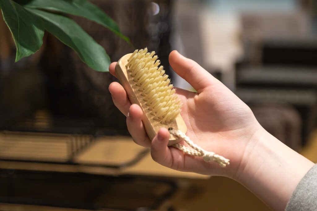 A bamboo brush being held in a hand, ideal for exfoliating and improving skin health.