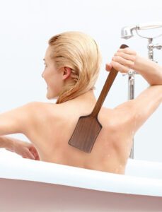 Bath brush with long handle made of dark wood and natural bristles, designed for dry body brushing and exfoliation.