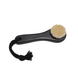 Black body dry brush with soft goat hair bristles and compact handle, designed for gentle exfoliation.