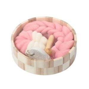 Christmas bath towel set displayed in a wooden bowl with bath sponges, foot care products, and massage accessories.