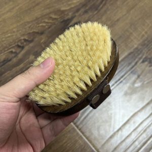 Wooden massage brush with boar bristle and hand strap, suitable for wet and dry use as a shower brush.
