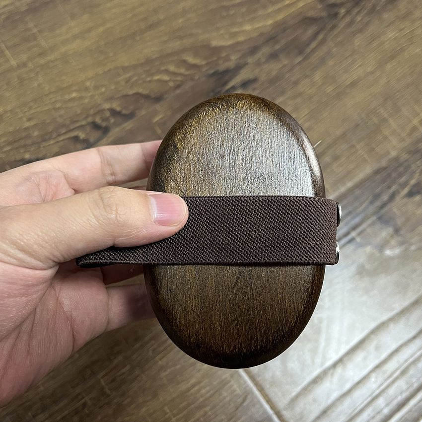 Wooden massage brush with boar bristle and hand strap, suitable for wet and dry use as a shower brush.