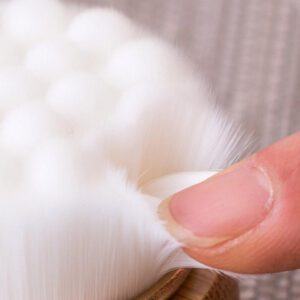 Shower back scrubber with a long wooden handle and soft cleansing pad, designed for bathing and body care.