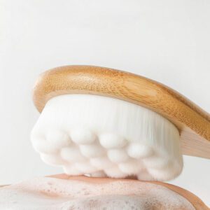 Shower back scrubber with a long wooden handle and soft cleansing pad, designed for bathing and body care.