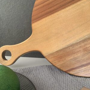 Round acacia wood cutting board featuring a handle, ideal for serving fruit, sushi, pizza, and steak, suitable for home kitchens and professional settings