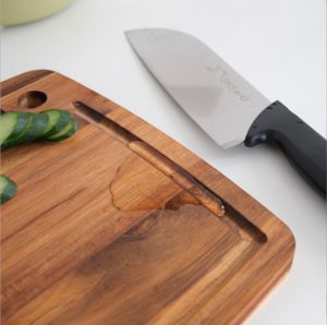 Rectangular acacia wood cutting board with built-in juice groove and hanging hole, ideal for chopping fruits, vegetables, and meats, suitable for kitchen use and serving