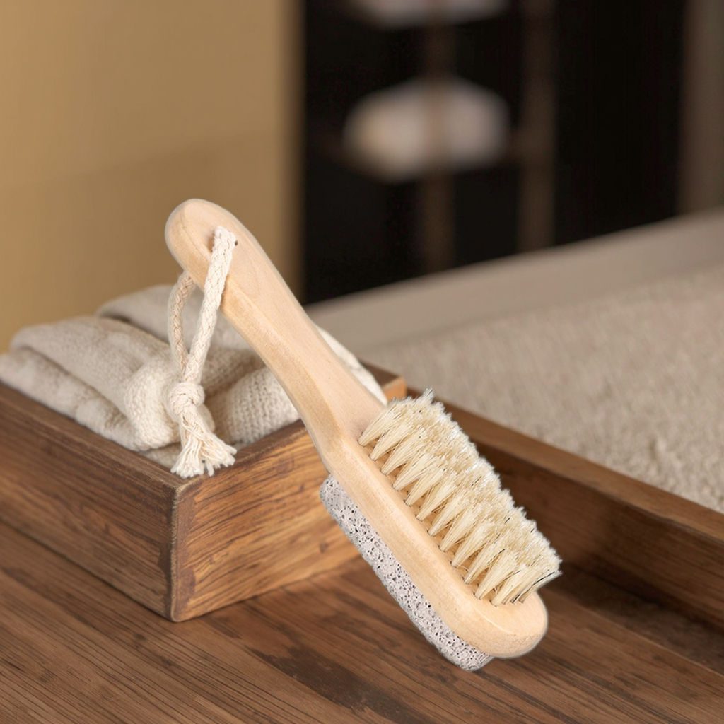 Wooden foot scrubber featuring natural boar bristles and pumice stone for exfoliating dead skin, cleaning feet, and removing callusesThis double-sided pumice stone foot scrubber is designed to provide a complete foot care experience by combining gentle cleansing and effective exfoliation in one convenient tool. One side features natural boar bristles that help remove dirt, refresh the skin, and stimulate circulation, while the pumice stone side works to reduce calluses, rough patches, and dry skin buildup. The smooth wooden handle offers a comfortable grip and precise control during use, making it suitable for both home pedicures and professional salon treatments. Lightweight and easy to store, the integrated hanging cord allows for quick drying and convenient organization. Ideal for maintaining soft heels and healthy-looking feet, this foot care file is widely used in spas, beauty salons, wellness centers, and personal grooming routines. JEYGO provides wholesale foot file manufacturing with OEM and ODM services, custom logo branding, private label packaging, and factory-direct pricing. A practical choice for beauty distributors, foot care brands, and retailers seeking durable and eco-friendly pedicure accessories.