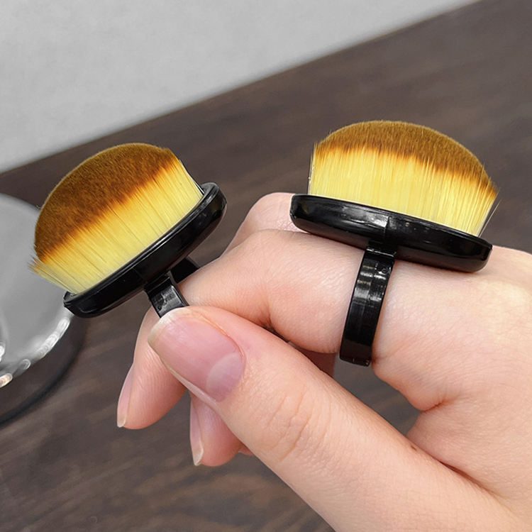 Compact round nail cleaning brush with soft synthetic bristles and black handle designed for removing nail art dust, powder, and manicure residue.