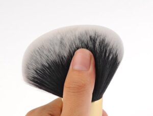 Professional vegan foundation makeup brush with dense black and white synthetic bristles, gold ferrule, and black handle for foundation, concealer, powder, and cosmetic blending.