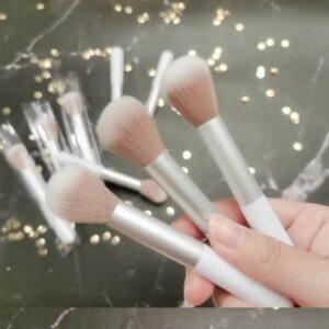 Compact single makeup brush with a white handle, silver ferrule, and soft synthetic bristles for foundation, blush, powder, and everyday cosmetic use.