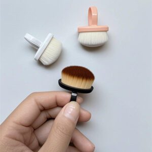 Compact round nail cleaning brush with soft synthetic bristles and black handle designed for removing nail art dust, powder, and manicure residue.