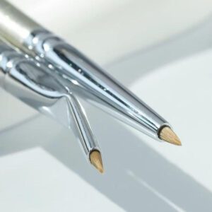 Professional fine-tip eyeliner and eyebrow brush with silver handle and synthetic bristles, designed for detailed eye makeup, brow shaping, and cosmetic precision work.